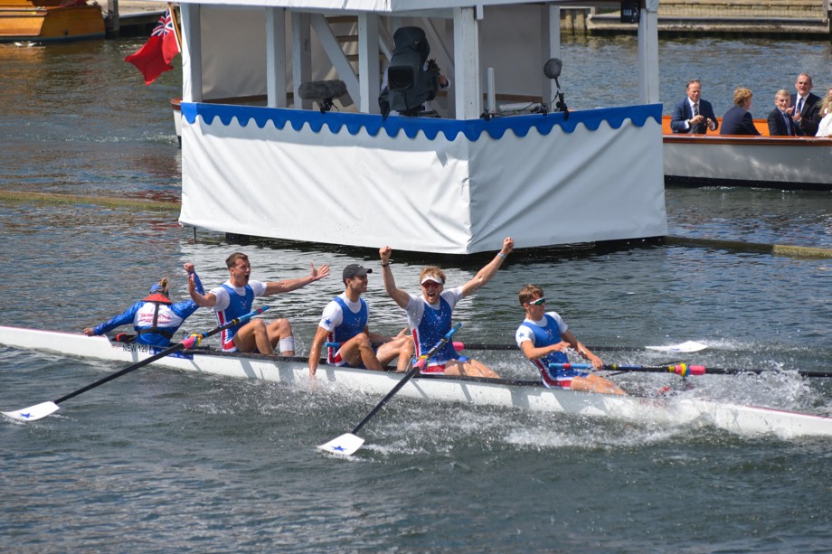 A men’s coxed four crossing the finish line, arms raised.